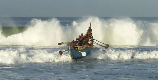 Traditional Kerala boat riding through sea waves near Alleppey